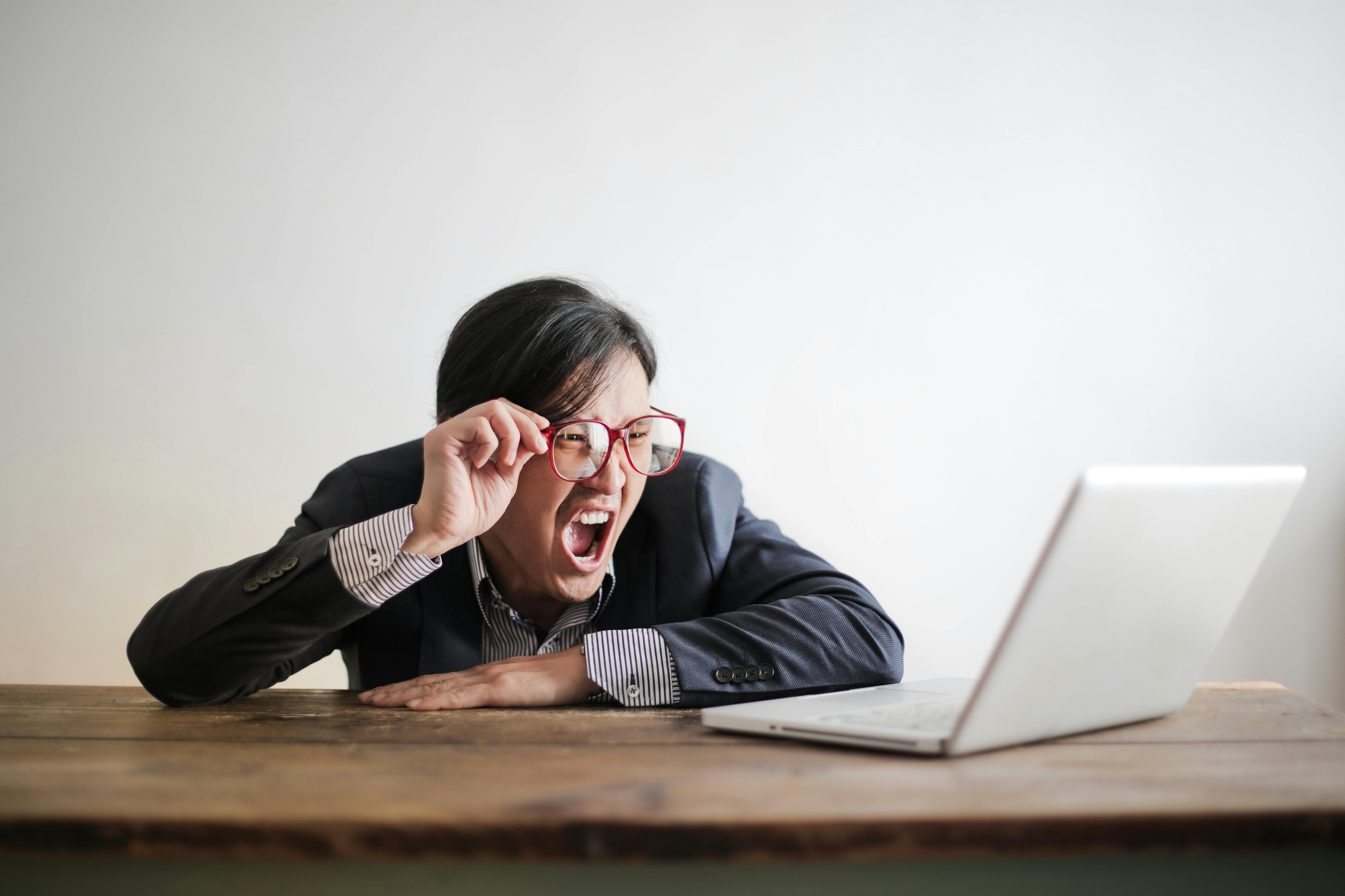 This image shows a man screaming at a laptop.